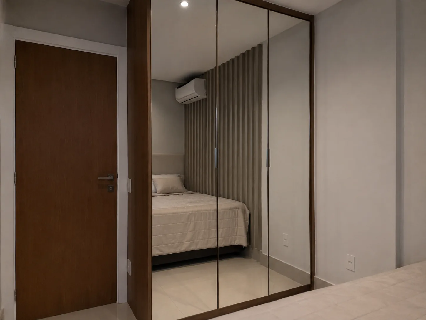 Guarda-roupas planejado com portas espelhadas e moldura amadeirada em suíte